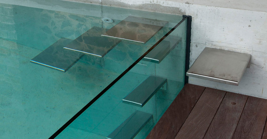 piscine à parois vitrées avec escalier inox