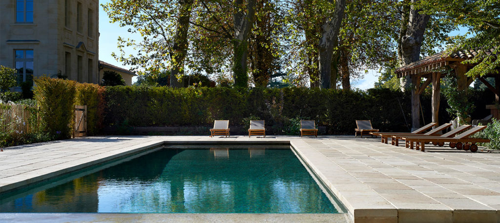 piscine à débordement en béton brut avec bains de soleil