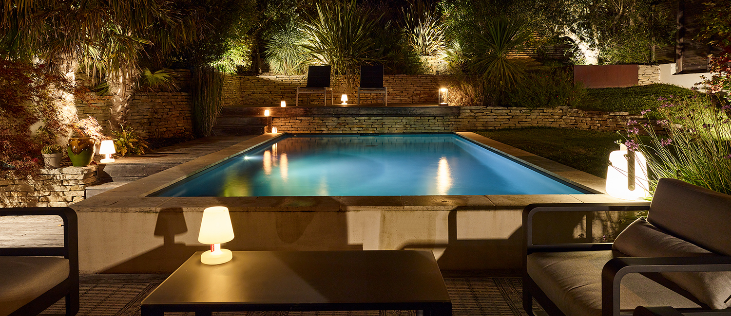 Mobilier tendance éclairage doux autour d’une petite piscine