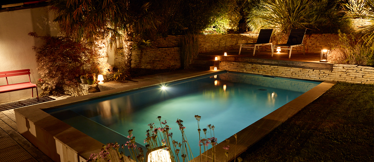 Mobilier tendance éclairage doux autour d’une petite piscine